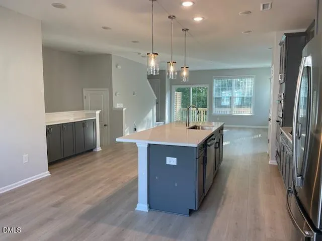 a kitchen with stainless steel appliances a stove a sink a refrigerator and a wooden floors