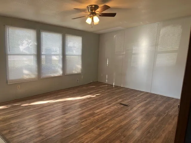 a view of empty room with wooden floor and fan