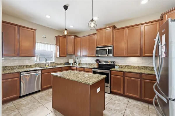 a kitchen with stainless steel appliances granite countertop a refrigerator a stove a sink and a microwave