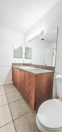 a white toilet sitting next to a bathroom sink and vanity