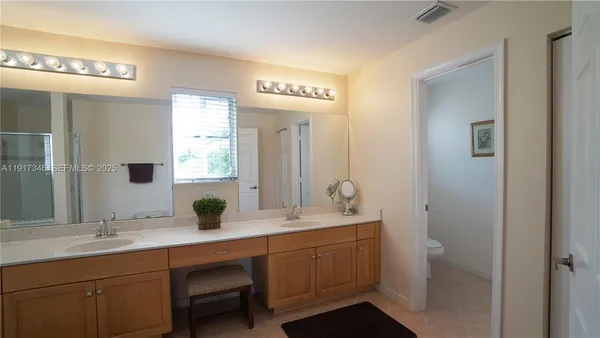 a bathroom with a double vanity sink a toilet a mirror and shower