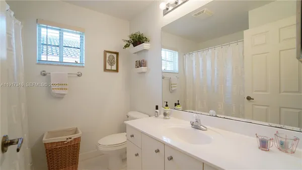 a bathroom with a granite countertop sink a toilet and a mirror