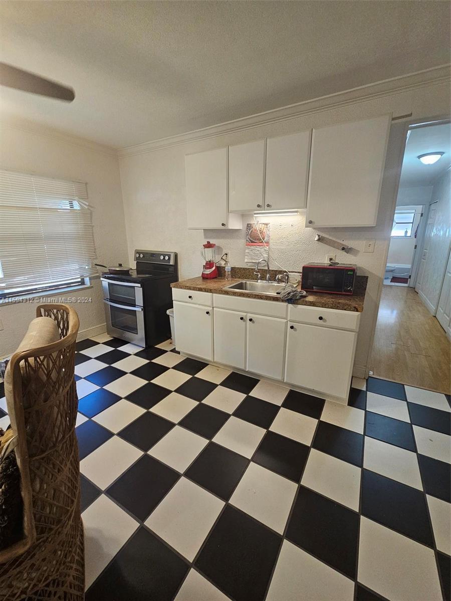 1107 Mayflower Road Fort Pierce, FL 34950 - Photo 15 of 21 a kitchen with a checkered floor and white cabinets