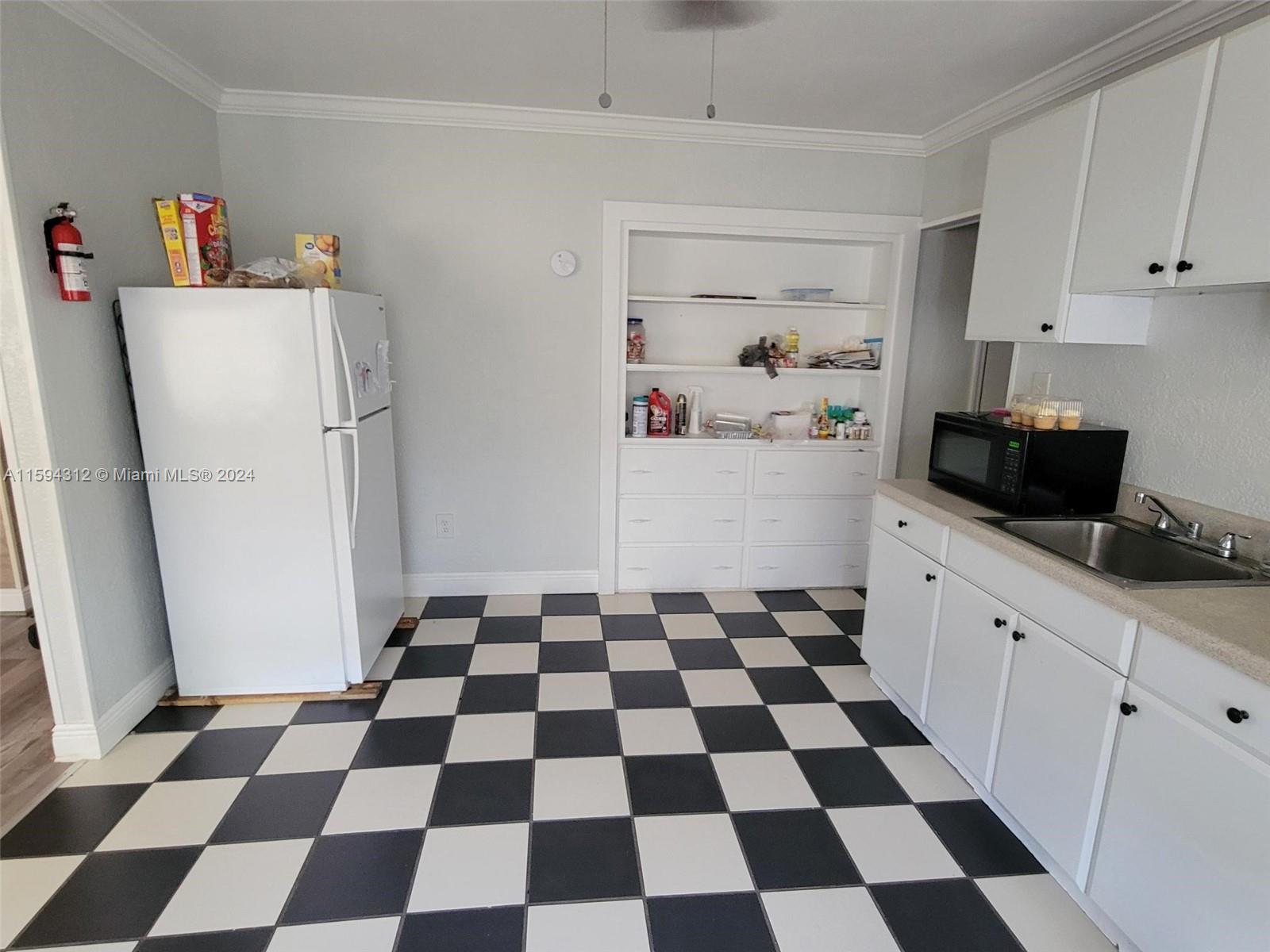1107 Mayflower Road Fort Pierce, FL 34950 - Photo 18 of 21 a kitchen with a checkered floor and white cabinets