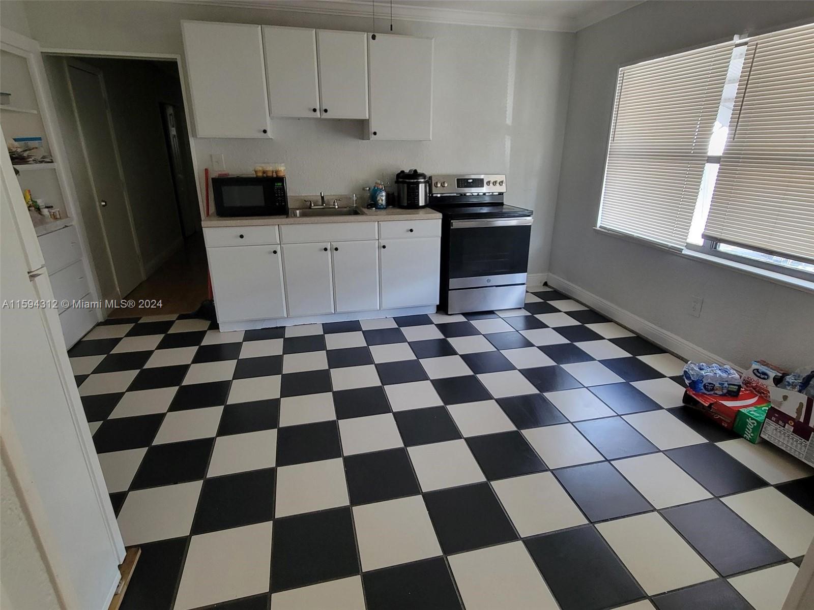 1107 Mayflower Road Fort Pierce, FL 34950 - Photo 19 of 21 a kitchen with a checkered floor and white cabinets