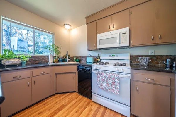 a kitchen with stainless steel appliances granite countertop a stove a sink dishwasher and cabinets with wooden floor