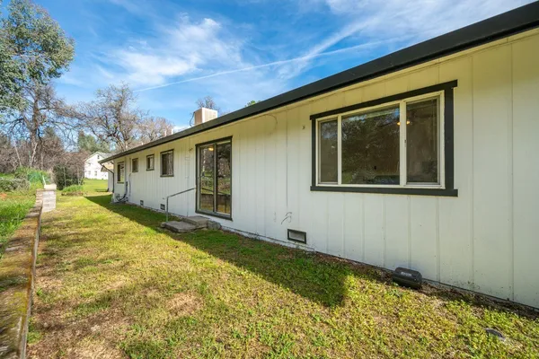 a view of an house with backyard and trees