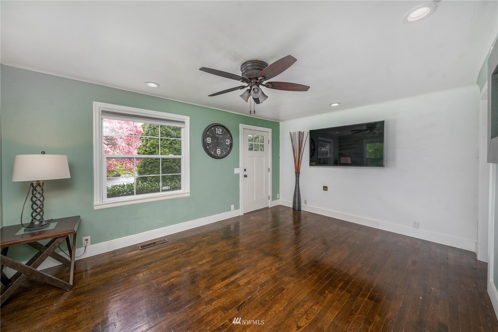 437 State Street Sumner, WA 98390 - Photo 8 of 25 a view of a livingroom with a flat screen tv wooden floor and a ceiling fan