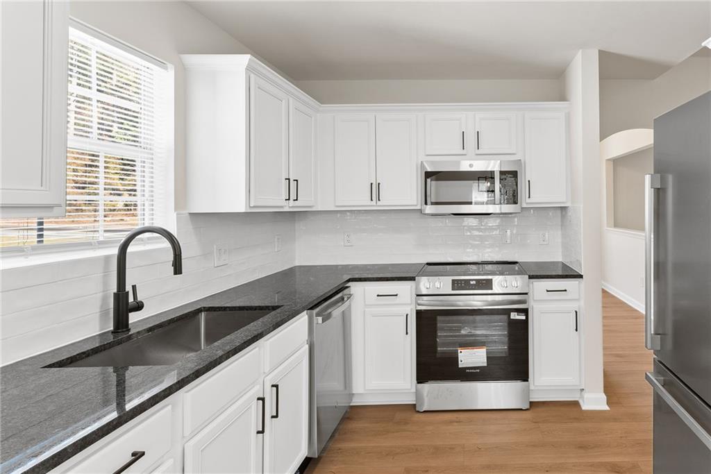 5805 Marbut Road Lithonia, GA 30058 - Photo 16 of 46 a kitchen with stainless steel appliances granite countertop a stove a sink and a microwave