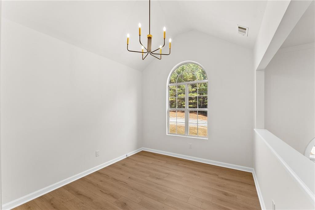 5805 Marbut Road Lithonia, GA 30058 - Photo 10 of 46 an empty room with chandelier fan and wooden floor