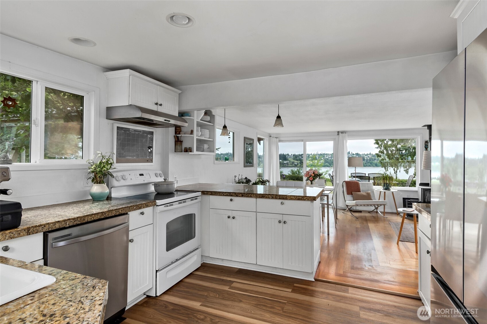 5222 East Harbor Road Freeland, WA 98249 - Photo 14 of 39 a kitchen with stainless steel appliances granite countertop a stove top oven a sink dishwasher a dining table and chairs with wooden floor