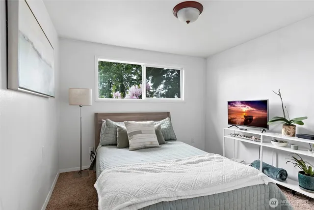 a bedroom with a bed and a flat tv screen on dresser