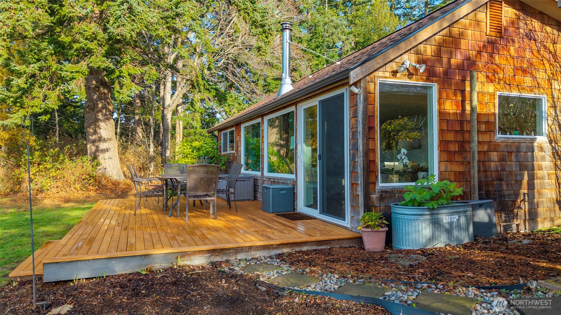 5222 East Harbor Road Freeland, WA 98249 - Photo 8 of 39 a view of a patio with table and chairs potted plants and floor to ceiling window