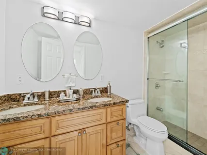 a bathroom with a granite countertop toilet a sink and a mirror