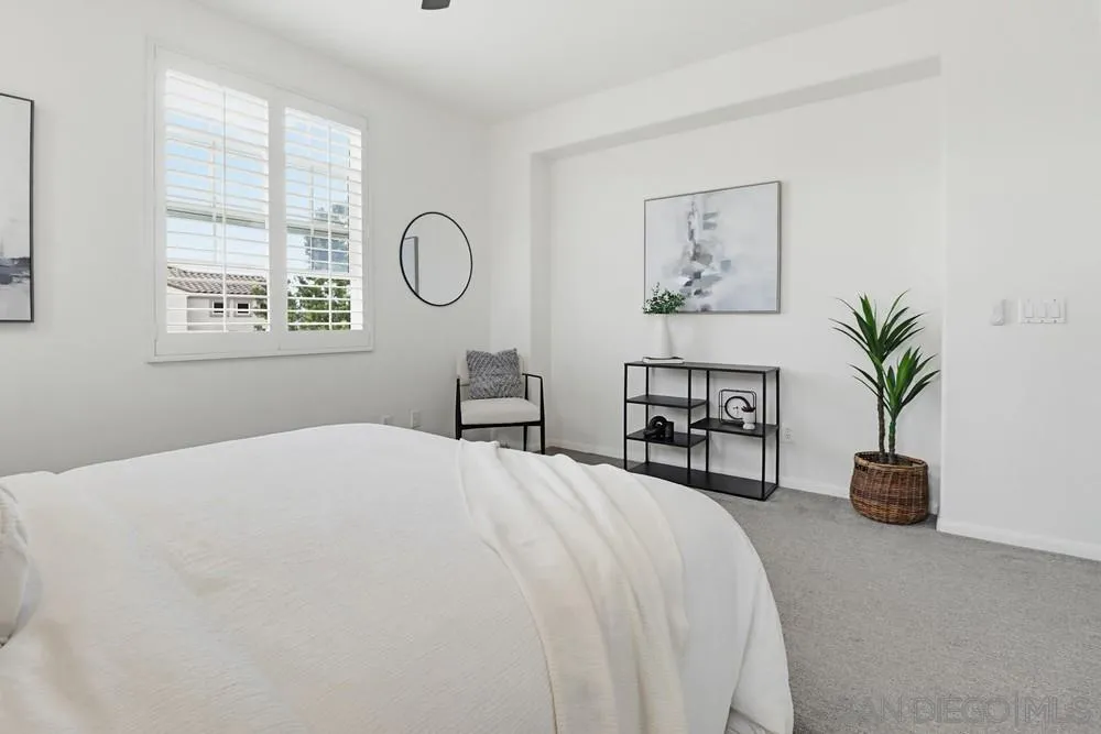 1293 Fools Gold Way, Unit 3 Chula Vista, CA 91913 - Photo 13 of 28 a spacious bedroom with a bed a chandelier and a window