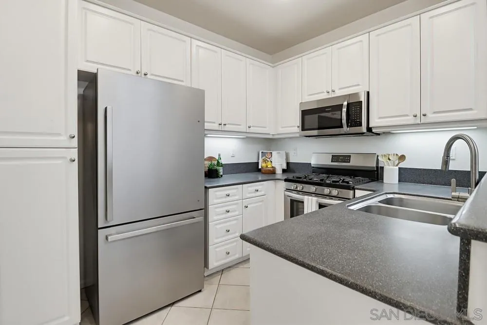1293 Fools Gold Way, Unit 3 Chula Vista, CA 91913 - Photo 8 of 28 a kitchen with stainless steel appliances white cabinets and a refrigerator