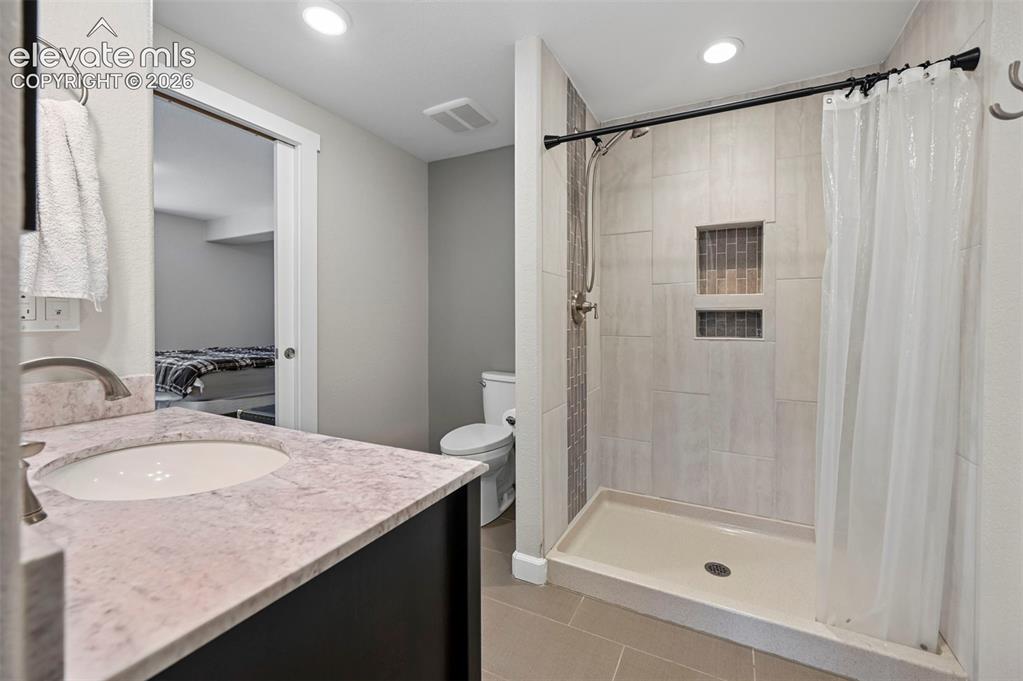 10643 Pictured Rocks Drive Peyton, CO 80831 - Photo 25 of 37 a bathroom with a granite countertop sink a mirror a vanity and a bathtub