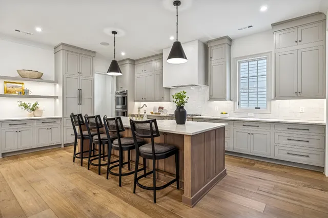 a kitchen with stainless steel appliances kitchen island granite countertop a table chairs sink and cabinets