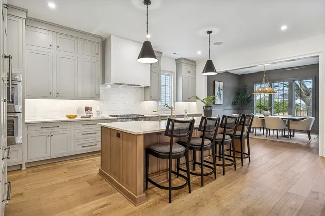 a open kitchen with granite countertop a stove a sink a dining table and chairs with wooden floor