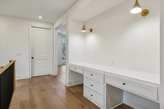 a view of an empty room with wooden floor and a ceiling fan