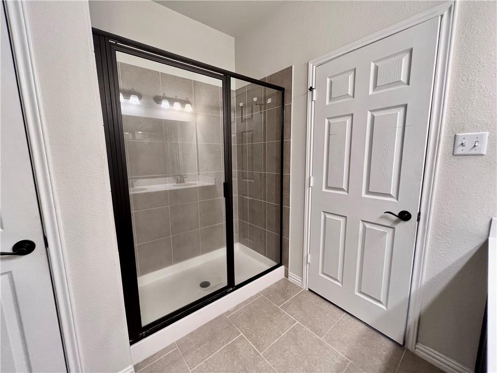 19733 Cherubini Trail Pflugerville, TX 78660 - Photo 11 of 24 Bathroom with a shower stall, a textured wall, and light tile patterned flooring