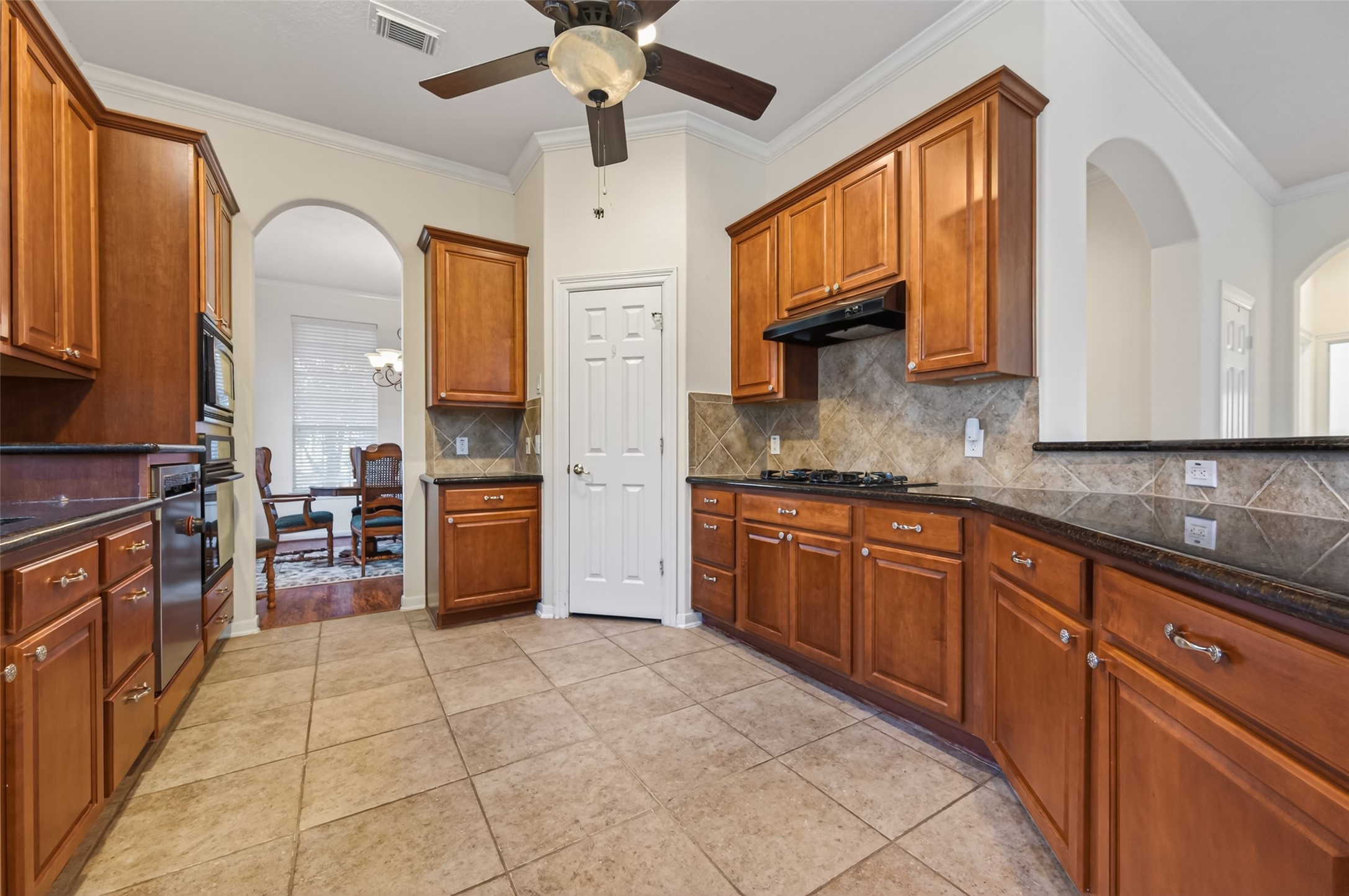 27 Sovereign Way Conroe, TX 77384 - Photo 17 of 49 This kitchen features warm wood cabinetry, tiled flooring, and a gas stove. It includes ample counter space.