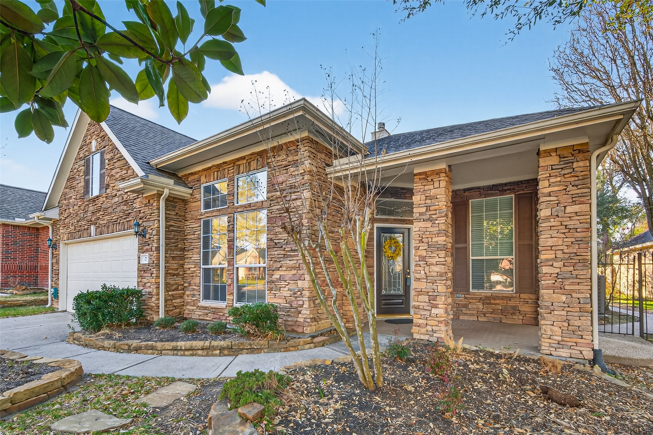 27 Sovereign Way Conroe, TX 77384 - Photo 2 of 49 Home features a rustic stone exterior, large windows, and a welcoming front porch.