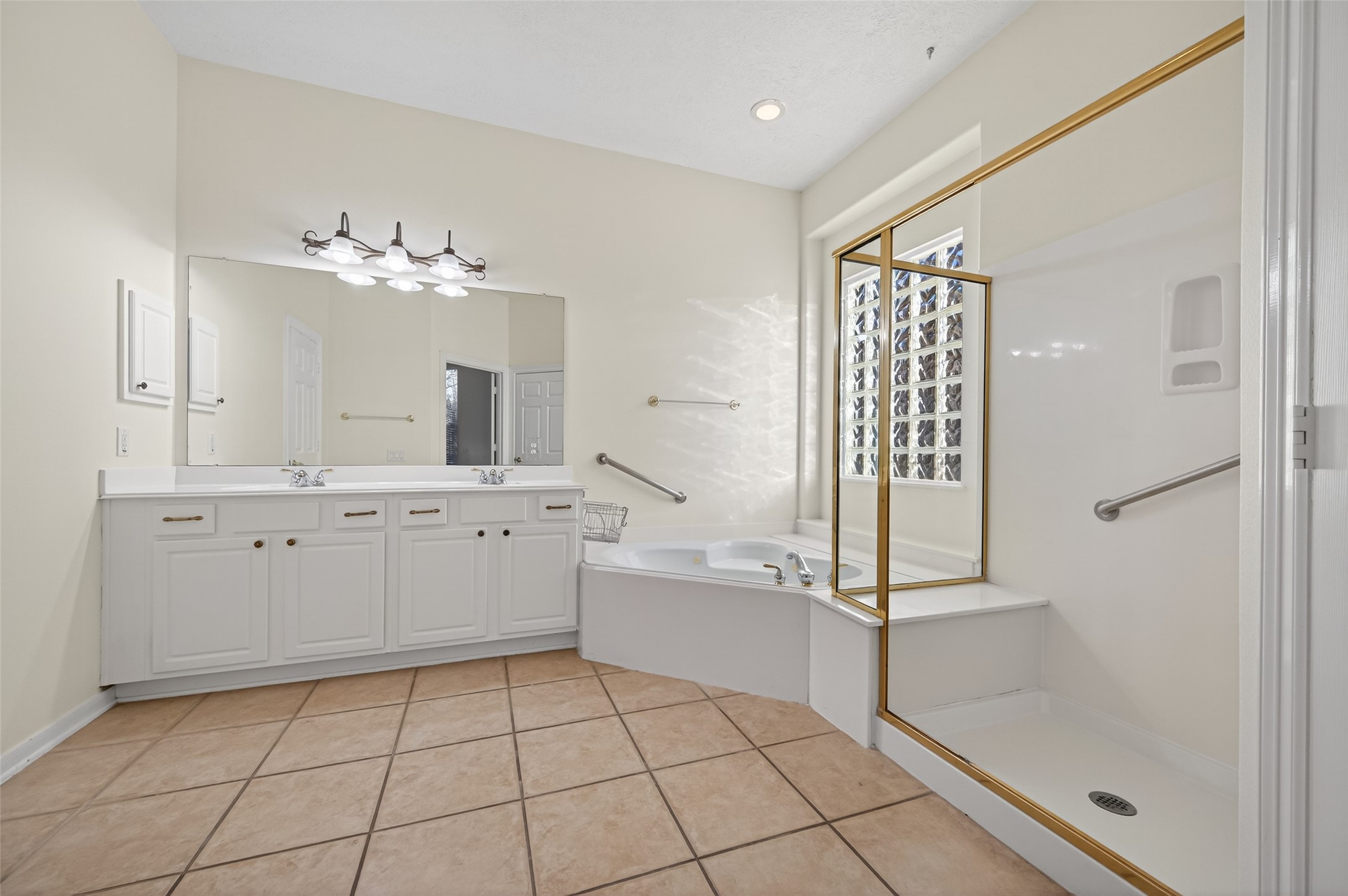 27 Sovereign Way Conroe, TX 77384 - Photo 23 of 49 Spacious bathroom with a large vanity featuring dual sinks and ample storage. It includes a corner soaking tub and a separate walk-in shower.