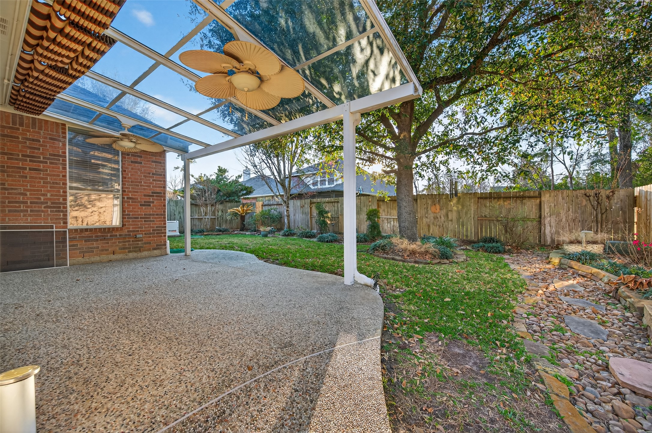 27 Sovereign Way Conroe, TX 77384 - Photo 33 of 49 This photo showcases a charming backyard with a covered patio featuring ceiling fans & retractable shades.