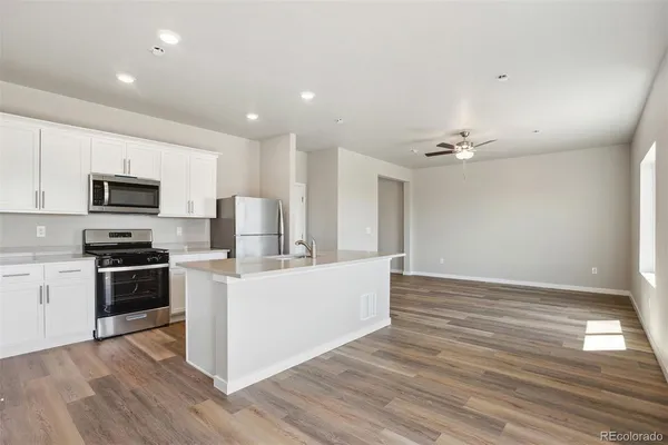 a living room with stainless steel appliances kitchen island granite countertop a sink and wooden floor