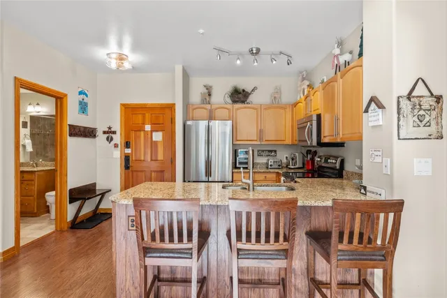 a kitchen with stainless steel appliances granite countertop a sink dishwasher a stove a refrigerator with a dining table and chairs