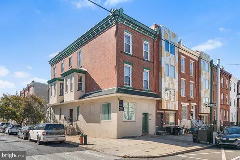 a front view of a building with lot of cars and trees