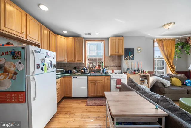 a kitchen with stainless steel appliances granite countertop a refrigerator a sink dishwasher a stove and white countertops with wooden floor