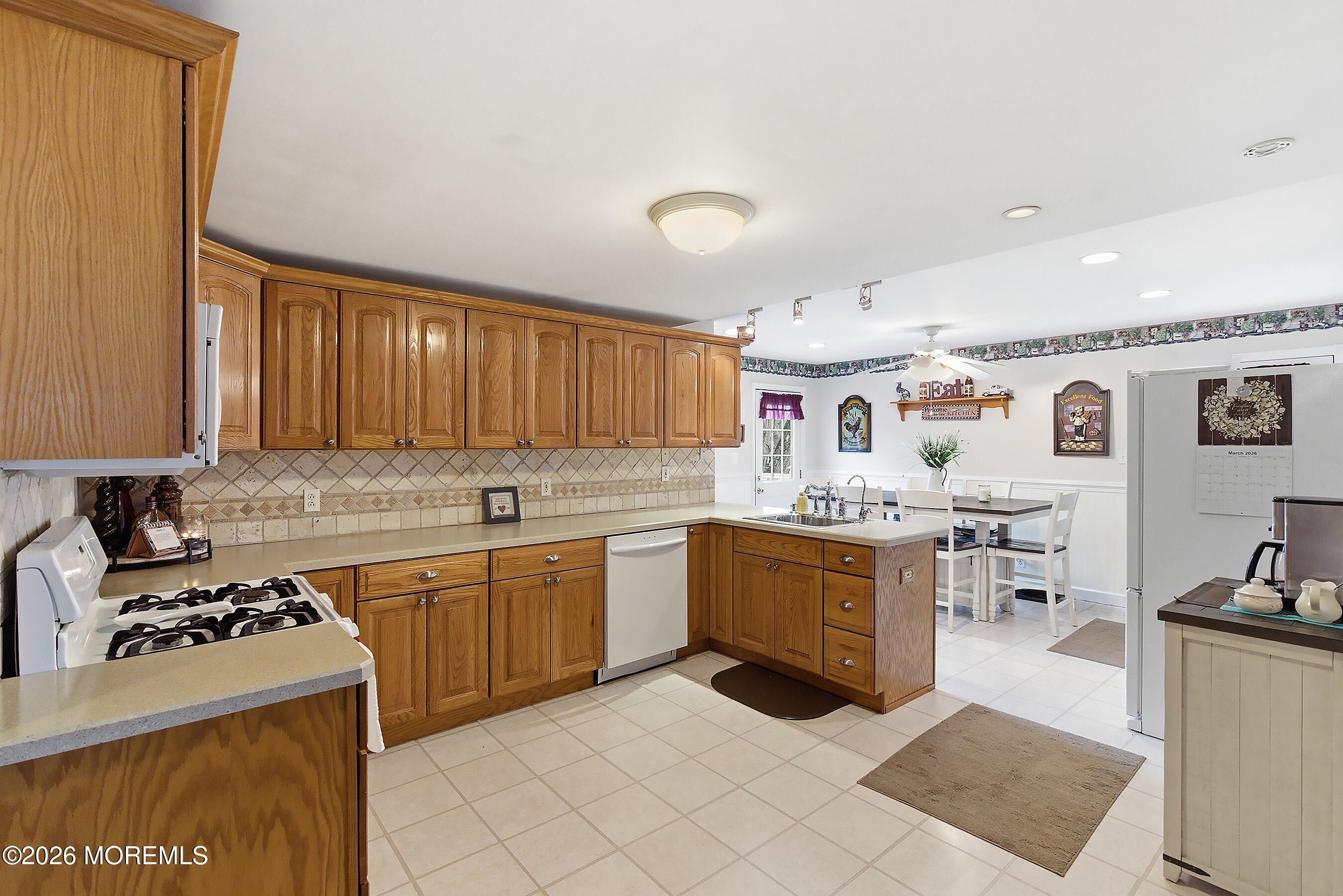 219 Stuart Street Howell, NJ 07731 - Photo 9 of 36 a kitchen with stainless steel appliances granite countertop a stove top oven a sink a dining table and chairs with white cabinets