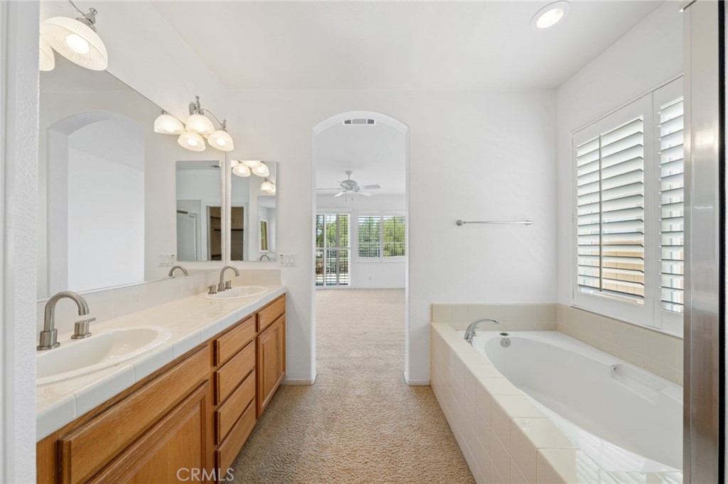 31256 Firestone Street Temecula, CA 92591 - Photo 32 of 56 a bathroom with a bathtub a double vanity sink a vanity a window and a mirror