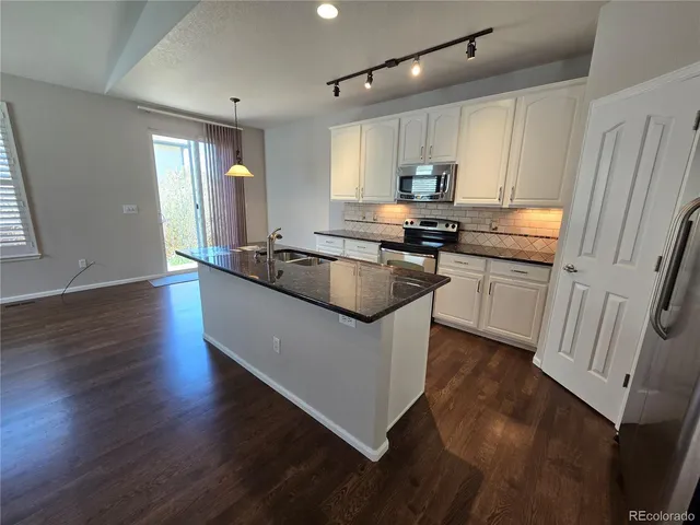 a kitchen with stainless steel appliances granite countertop a sink a stove a refrigerator and cabinets