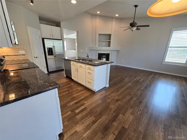 a large kitchen with stainless steel appliances a large counter top a stove a sink and a refrigerator