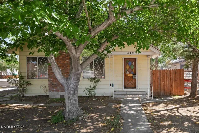 a front view of a house with a tree