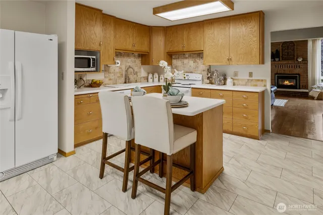 a kitchen with stainless steel appliances kitchen island granite countertop a sink a stove a refrigerator cabinets and chairs