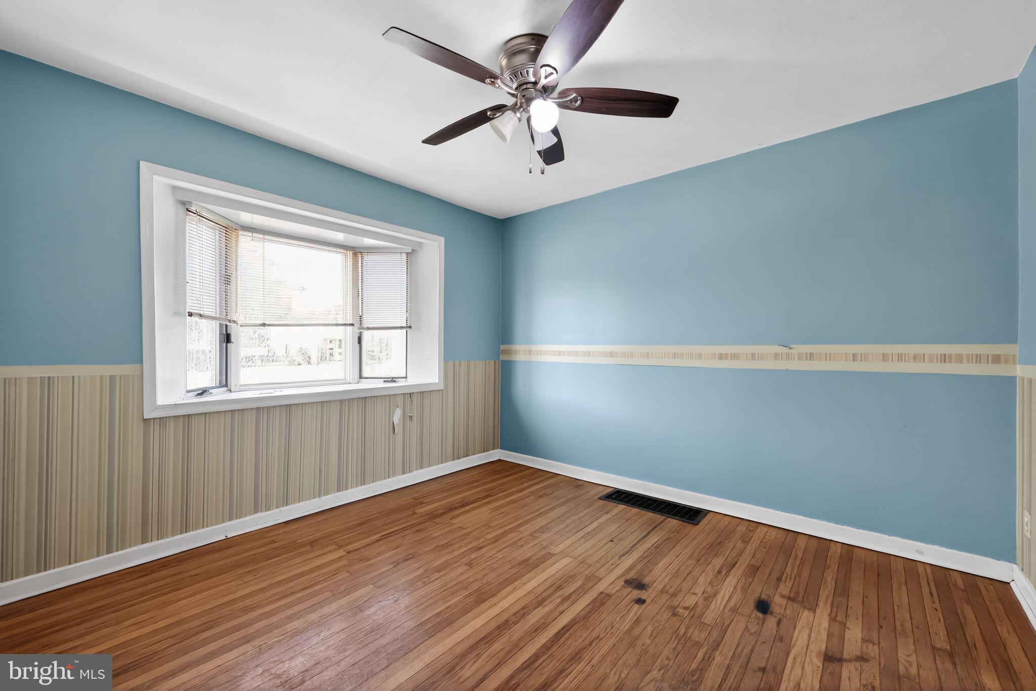 1212 Meadow Road Woodlyn, PA 19094 - Photo 12 of 30 an empty room with wooden floor chandelier fan and windows