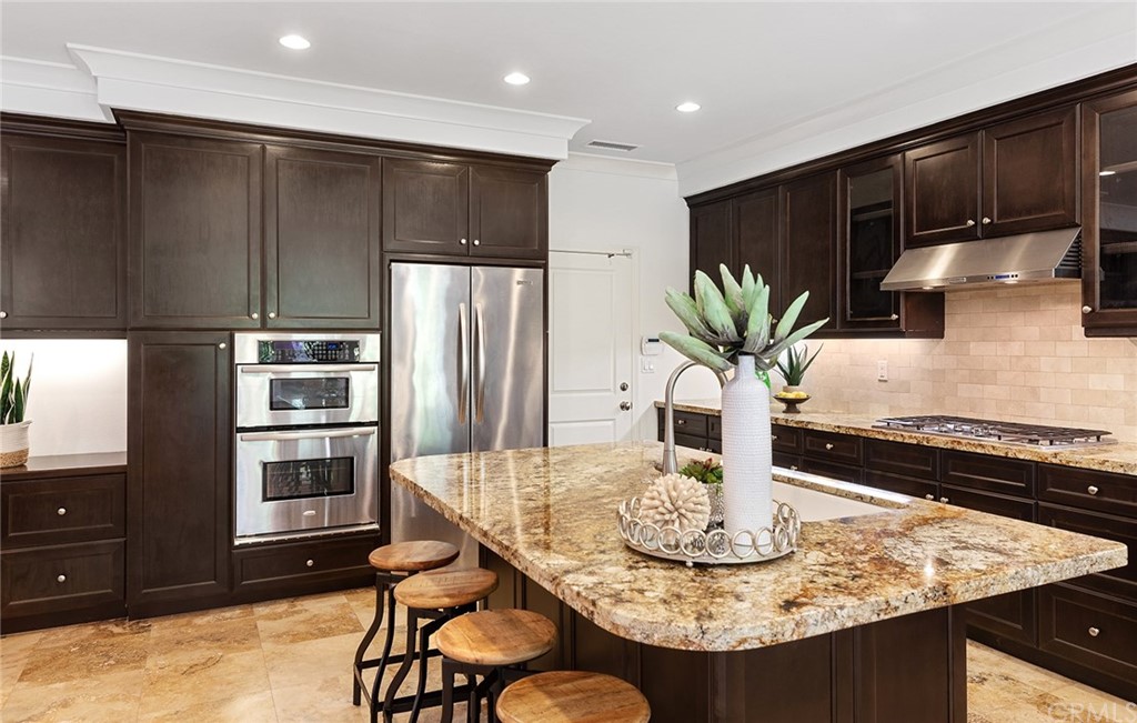 62 Cipresso Irvine, CA 92618 - Photo 9 of 49 a kitchen with stainless steel appliances kitchen island granite countertop a refrigerator a stove a sink and a dining table with wooden floor
