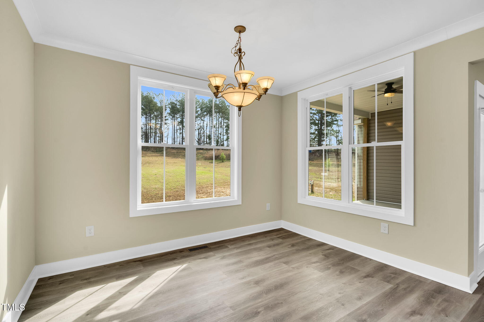 1076 Highway 55 Coats, NC 27521 - Photo 5 of 20 an empty room with wooden floor chandelier and windows