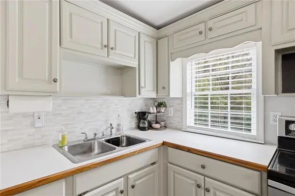 a kitchen with stainless steel appliances white cabinets a sink and a window