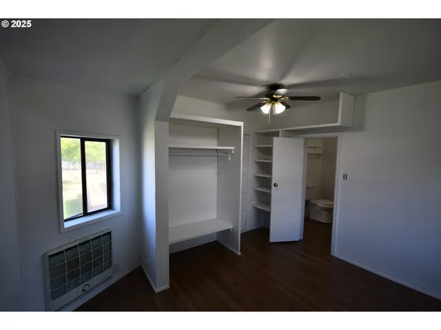 a view of an empty room with a ceiling fan and window