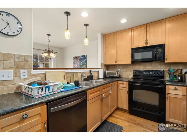 a kitchen with granite countertop a sink a stove top oven and wooden cabinetry