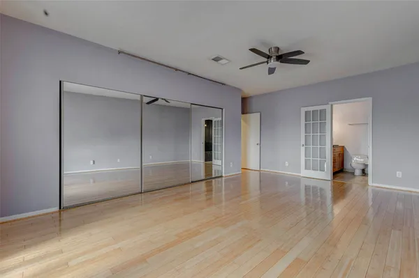 a view of empty room with wooden floor and ceiling fan