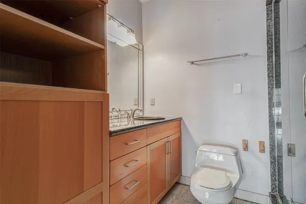 a bathroom with a granite countertop toilet sink and mirror