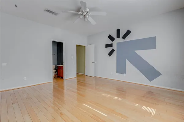 a view of an empty room with a ceiling fan and wooden floor