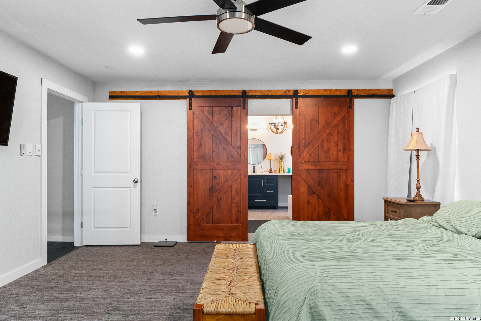 15285 South Skaggs Road Atascosa, TX 78002 - Photo 21 of 36 a bedroom with a bed and a chandelier