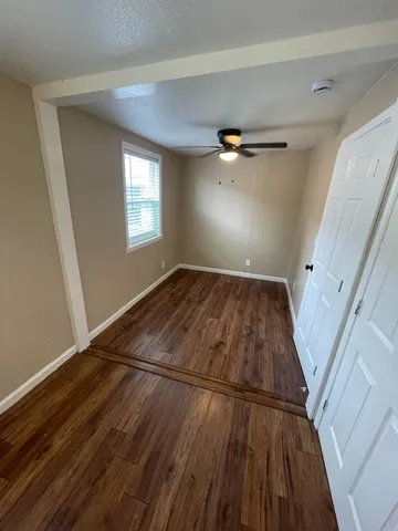 a view of an empty room with wooden floor and a window